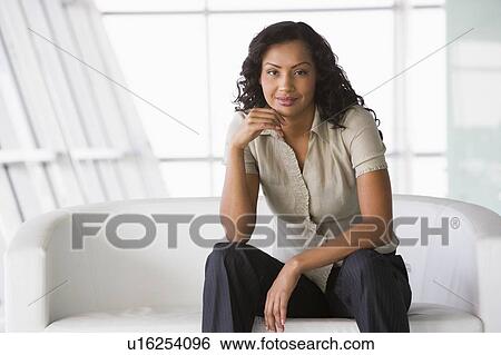 Businesswoman sitting indoors smiling (high key/selective focus) View Large Photo Image Stock Photograph - Businesswoman sitting indoors smiling (high key/selective focus). Fotosearch