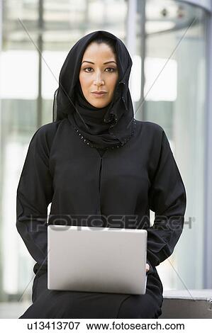 Businesswoman sitting outdoors with laptop by building (selective focus) View Large Photo Image Stock Photo - Businesswoman sitting outdoors with laptop by building (selective focus). Fotosearch