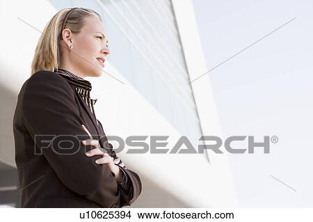 Picture - Businesswoman standing outdoors by building. Fotosearch