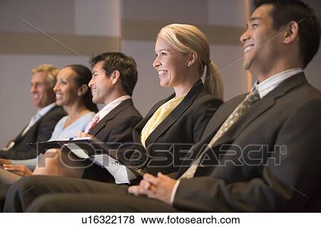 Stock Photo - Five businesspeople smiling in presentation room with clipboards. Fotosearch