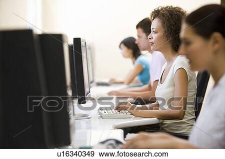 Stock Photo - Four people sitting in computer room typing. Fotosearch