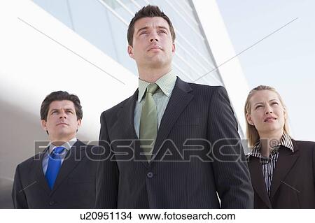 Three businesspeople standing outdoors by building View Large Photo Image Picture - Three businesspeople standing outdoors by building. Fotosearch