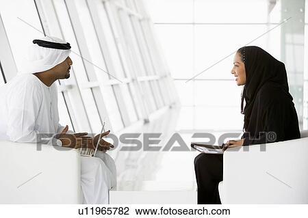 Two businesspeople indoors with a laptop talking and smiling (high key/selective focus) View Large Photo Image Stock Image - Two businesspeople indoors with a laptop talking and smiling (high key/selective focus). Fotosearch