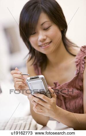 Woman in computer room using personal digital assistant smiling View Large Photo Image Stock Image - Woman in computer room using personal digital assistant smiling. Fotosearch