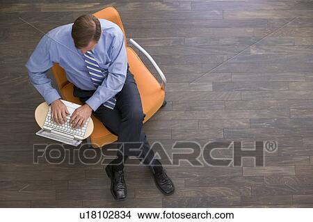 Picture - Businessman sitting indoors with laptop. Fotosearch