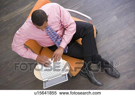 Businessman sitting indoors with laptop View Large Photo Image Stock Photography - Businessman sitting indoors with laptop. Fotosearch