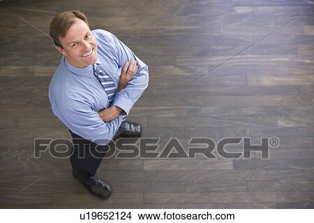 Picture - Businessman standing indoors smiling. Fotosearch