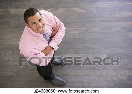 Businessman standing indoors smiling View Large Photo Image Stock Image - Businessman standing indoors smiling. Fotosearch