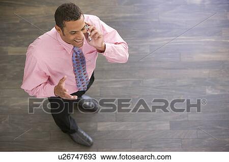 Businessman standing indoors using cellular phone smiling View Large Photo Image Stock Image - Businessman standing indoors using cellular phone smiling. Fotosearch