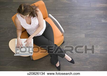 Picture - Businesswoman sitting indoors with laptop. Fotosearch