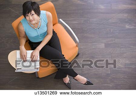 Stock Photo - Businesswoman sitting indoors with laptop. Fotosearch