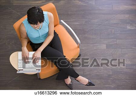 Businesswoman sitting indoors with laptop View Large Photo Image Stock Photograph - Businesswoman sitting indoors with laptop. Fotosearch