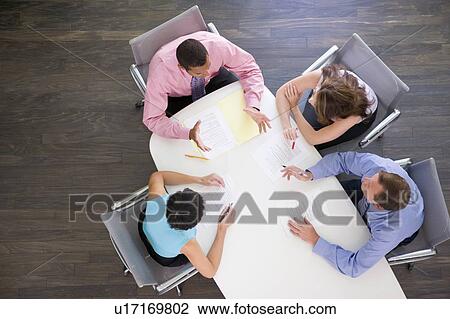 Stock Image - Four businesspeople at boardroom table. Fotosearch