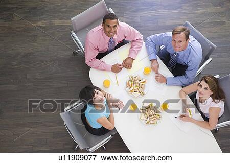 Four businesspeople at boardroom table with sandwiches smiling View Large Photo Image Stock Photo - Four businesspeople at boardroom table with sandwiches smiling. Fotosearch