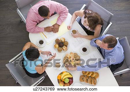 Four businesspeople at boardroom table with breakfast View Large Photo Image Stock Photo - Four businesspeople at boardroom table with breakfast. Fotosearch