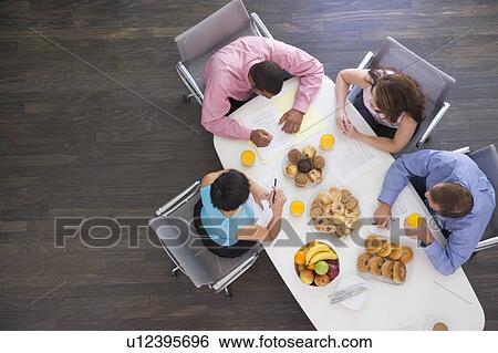 Four businesspeople at boardroom table with breakfast View Large Photo Image Stock Photograph - Four businesspeople at boardroom table with breakfast. Fotosearch