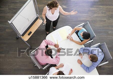 Four businesspeople at boardroom table watching presentation View Large Photo Image Stock Photograph - Four businesspeople at boardroom table watching presentation. Fotosearch