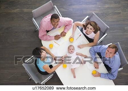 Stock Photo - Four businesspeople in boardroom with a baby lying on the table. Fotosearch