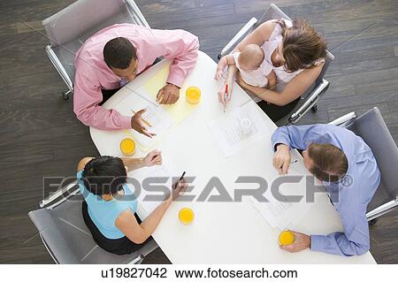 Four businesspeople in boardroom with one holding a baby View Large Photo Image Stock Image - Four businesspeople in boardroom with one holding a baby. Fotosearch
