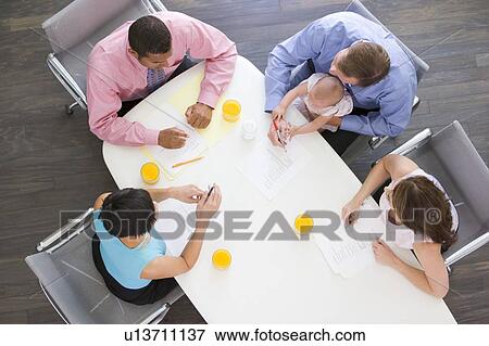 Stock Photo - Four businesspeople in boardroom with one holding a baby. Fotosearch
