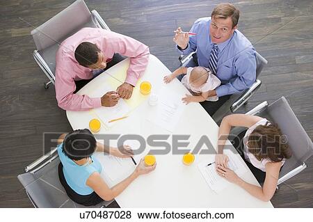 Four businesspeople in boardroom with one holding a baby View Large Photo Image Stock Photo - Four businesspeople in boardroom with one holding a baby. Fotosearch