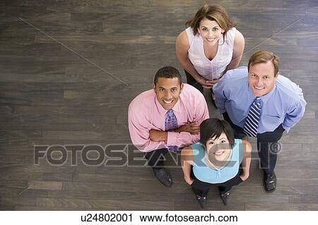 Four businesspeople standing indoors smiling View Large Photo Image Stock Image - Four businesspeople standing indoors smiling. Fotosearch