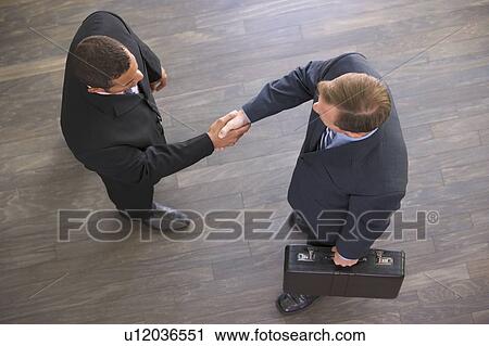 Two businessmen indoors shaking hands View Large Photo Image Stock Image - Two businessmen indoors shaking hands. Fotosearch