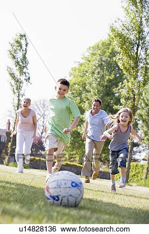 Stock Photograph - Family outdoors playing soccer and having fun. Fotosearch