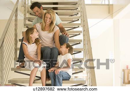 Stock Image - Family sitting on staircase smiling. Fotosearch