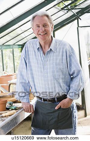 Stock Photo - Man in greenhouse smiling. Fotosearch