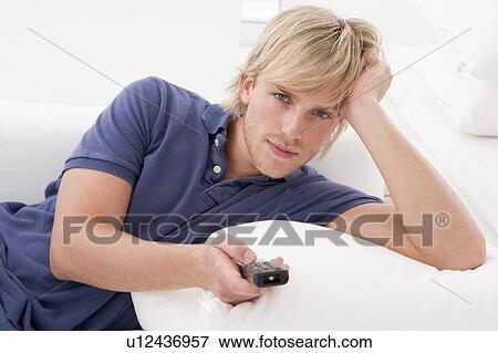 Man in living room holding remote control View Large Photo Image Stock Photo - Man in living room holding remote control. Fotosearch