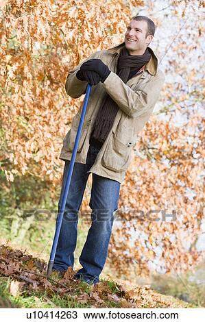 Man outdoors raking leaves and smiling (selective focus) View Large Photo Image Stock Image - Man outdoors raking leaves and smiling (selective focus). Fotosearch