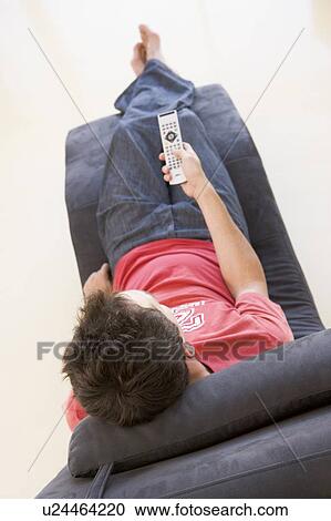 Man sitting in chair using remote control View Large Photo Image Stock Image - Man sitting in chair using remote control. Fotosearch