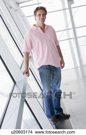 Picture - Man standing in corridor smiling. Fotosearch