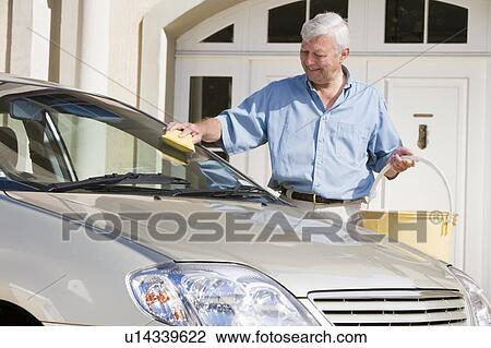 Stock Image - Senior man washing his car outside house. Fotosearch