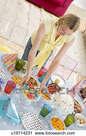 Woman at party setting out food and smiling View Large Photo Image Stock Image - Woman at party setting out food and smiling. Fotosearch