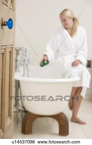 Stock Photo - Woman in bathroom putting bubble bath in bathtub. Fotosearch
