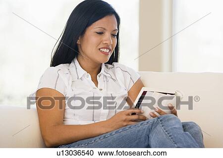 Woman in living room reading book smiling View Large Photo Image Stock Image - Woman in living room reading book smiling. Fotosearch