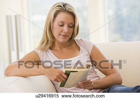 Stock Photography - Woman in living room reading book. Fotosearch