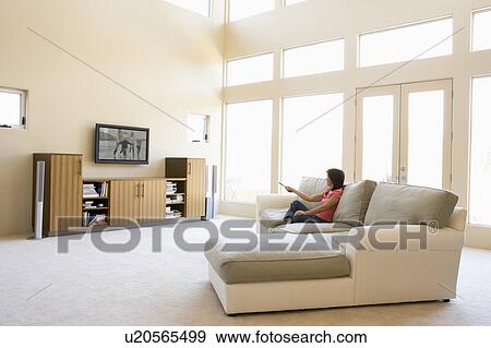 Stock Photo - Woman in living room watching television. Fotosearch