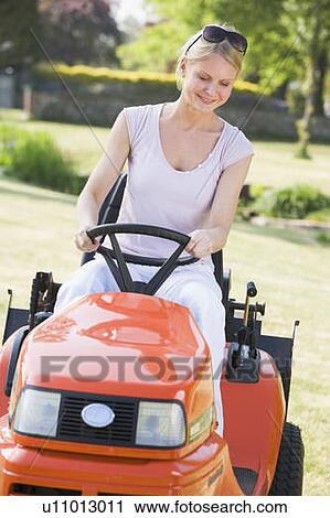 Woman outdoors driving lawnmower smiling View Large Photo Image Stock Image - Woman outdoors driving lawnmower smiling. Fotosearch