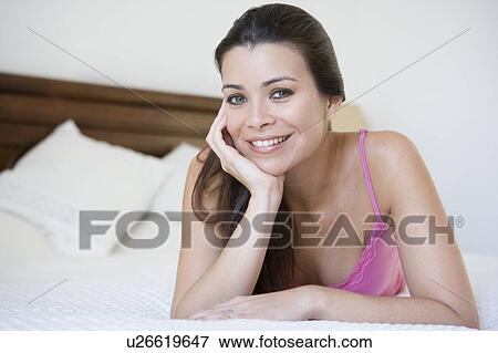 Stock Photo - Woman relaxing on bed in bedroom smiling (selective focus). Fotosearch