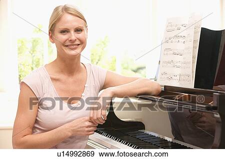 Woman sitting at piano and smiling View Large Photo Image Stock Photo - Woman sitting at piano and smiling. Fotosearch