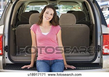 Stock Image - Woman sitting in back of van smiling. Fotosearch