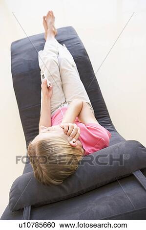 Stock Image - Woman sitting in chair listening to MP3 player. Fotosearch