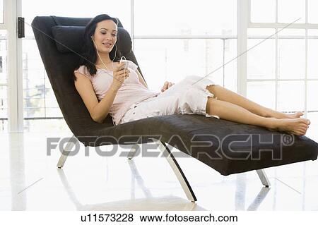 Woman sitting in chair listening to MP3 player smiling View Large Photo Image Stock Photo - Woman sitting in chair listening to MP3 player smiling. Fotosearch