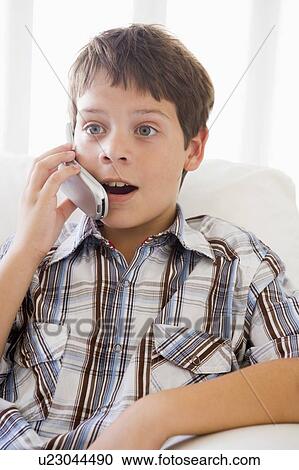 Young Boy Sitting On A Sofa Talking On A Mobile Phone View Large Photo Image Stock Image - Young Boy Sitting On A Sofa Talking On A Mobile Phone. Fotosearch