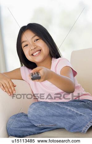 Young girl in living room with remote control smiling View Large Photo Image Stock Photography - Young girl in living room with remote control smiling. Fotosearch