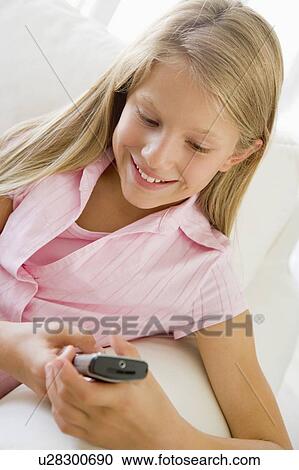 Young Girl Sitting On A Sofa Texting On A Cellphone View Large Photo Image Stock Image - Young Girl Sitting On A Sofa Texting On A Cellphone. Fotosearch