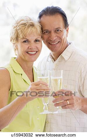 Stock Image - Couple toasting champagne and smiling. Fotosearch